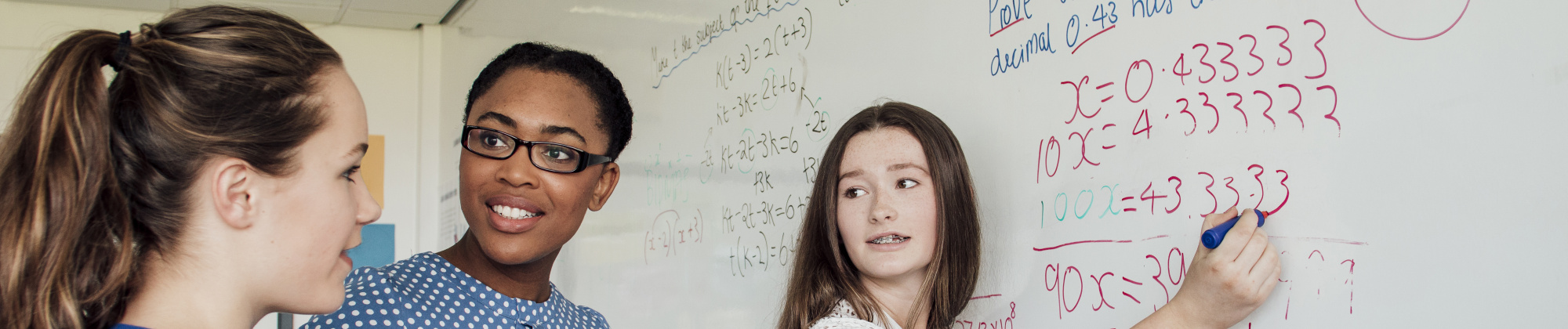 students and a teacher at a whiteboard doing math problems