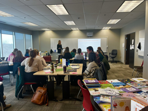 Teachers and mentors collaborating at many tables in a meeting room