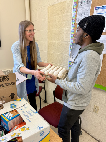 A staff member passes a crate of eggs to a student at BFEC.
